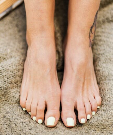 Nahaufnahme von den pedikürten Füßen einer Frau, die auf einer weichen Decke ruhen und Entspannung und Einfachheit ausstrahlen.